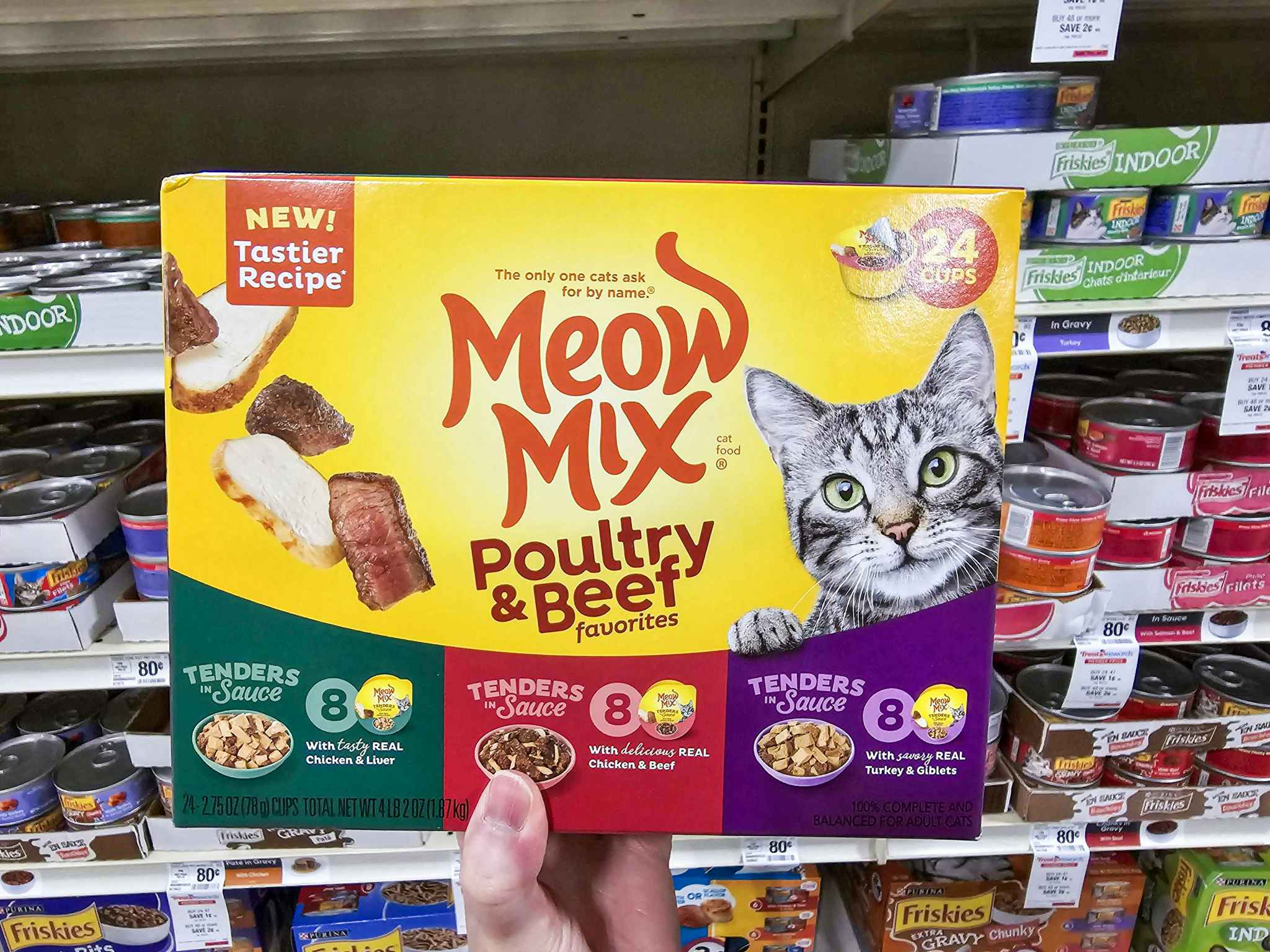 person holding a box of meow mix cat food in front of the shelf