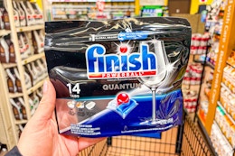 hand holding a pack of finish dishwasher tablets