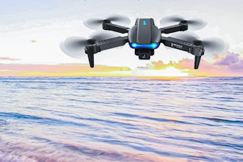 Lifestyle image of a Beeprincess drone with camera flying over body of water