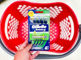 hand holding a pack of gillette razors over a target basket