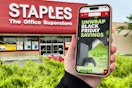 someone holding a phone showing the black friday ad in front of a staples store