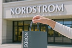 someone holding a shopping bag outside of Nordstrom