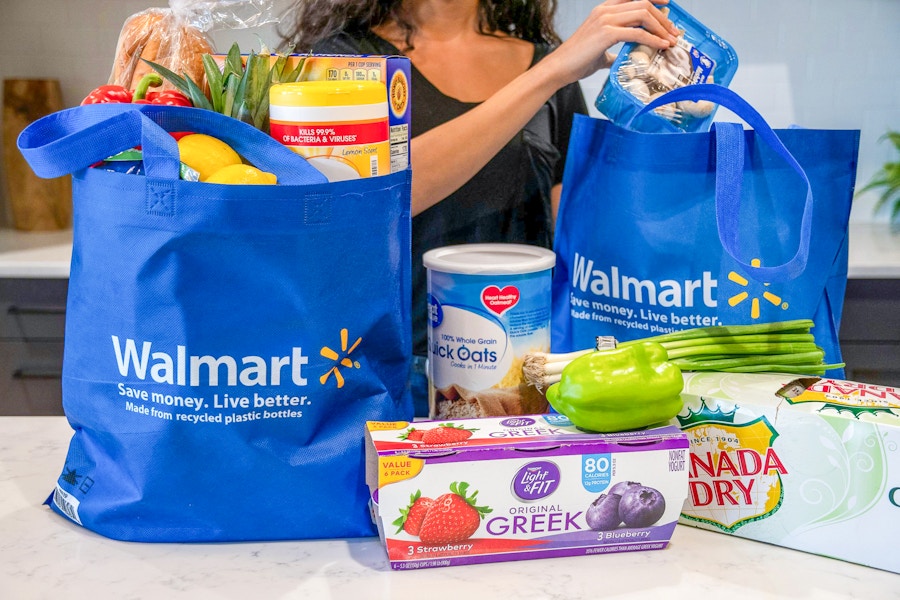 A woman pulling groceries out of Walmart reusable grocery bags.