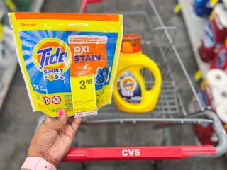hand holding one Tide Simply Pods with sales tag attached and Tide Simply liquid detergent inside cart