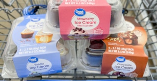 Three packs of great value ice cream filled cupcakes in a walmart shopping cart: vanilla, strawberry, and chocolate flavors
