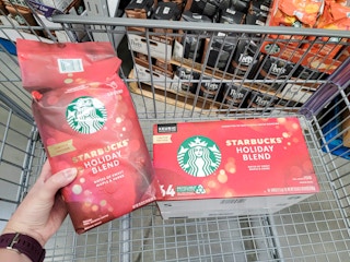 hand holding a bag of starbucks holiday blend coffee by a box of kcups