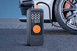 BEVA Tire Inflator Portable Air Compressor on the ground by a car tire.