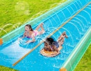 two kids sliding on a water slide 