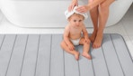 a mom drying a baby hair on a grey bath mat