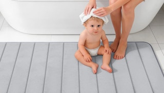 a mom drying a baby hair on a grey bath mat