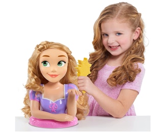A girl playing with a Rapunzel styling head.