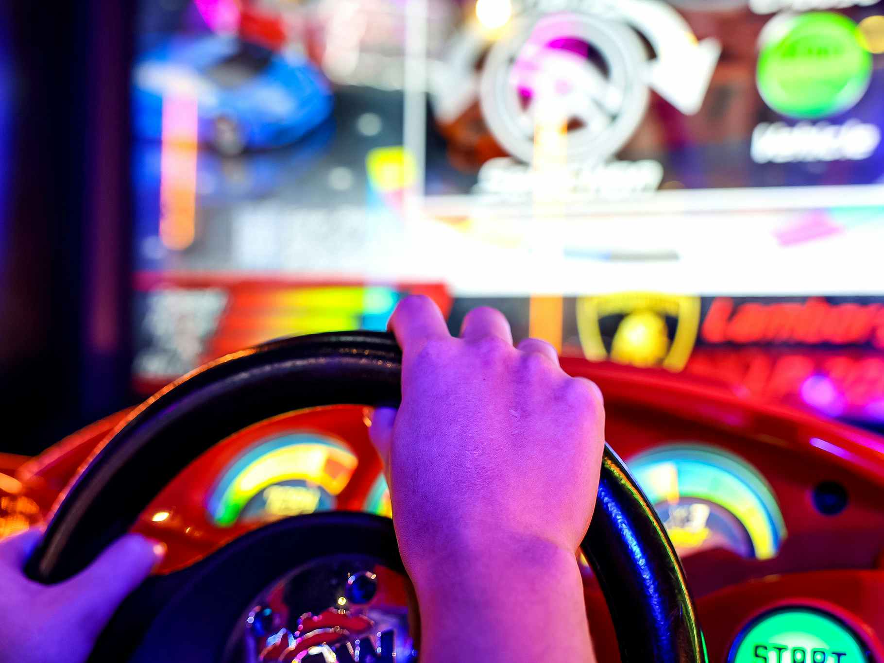 persons hands on wheel playing arcade game at dave and busters