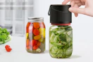 a vacuum sealer on jars of pickled vegetables