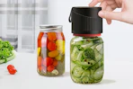 a vacuum sealer on jars of pickled vegetables