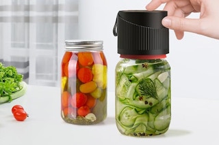 a vacuum sealer on jars of pickled vegetables