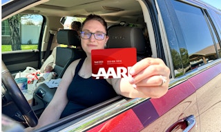 a woman holding an aarp card while sitting in a car