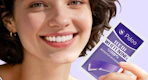 a person holding a purple pack of teeth whitening strips