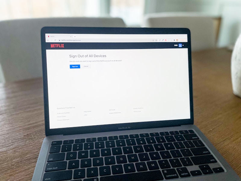 laptop showing netflix.com account settings with option to sign out of netflix on all devices