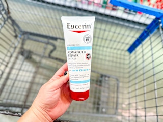 hand holding a bottle of Eucerin body cream