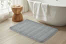 lifestyle image of a gray bath mat in front of a tub