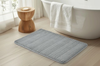 lifestyle image of a gray bath mat in front of a tub