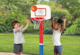 two toddlers playing with an adjustable basketball hoop