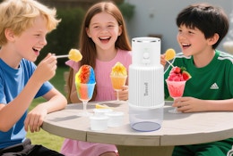 kids sitting at a table with snow cones and a snow cone machine