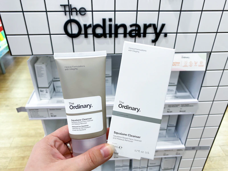 a hand holding a skincare product in front of a display 
