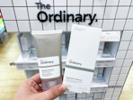 a hand holding a skincare product in front of a display