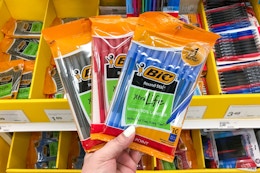hand holding 3 packs of bic pens in front of a target shelf