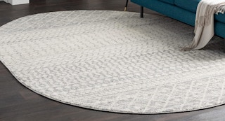 an oval grey patterned area rug on a wooden floor