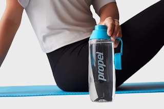 Lifestyle image of person holding a Propel water bottle on a yoga mat