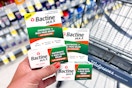 hand holding two packs of bactine max ointment in front of walgreens shopping cart in store aisle