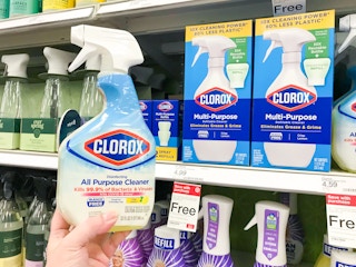 hand holding bottle of clorox in front of self with cleaning products