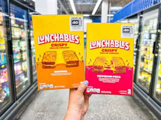 hand holding two lunchables grilled cheesies boxes in walmart aisle