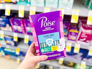 person holding poise pads in front of a shelf