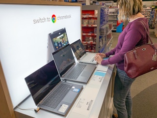 A woman looking down and using the touch pad on a Chromebook on display at Best Buy.