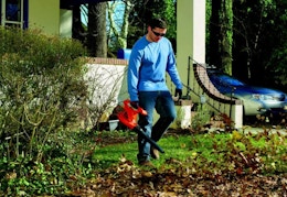 a person using a leaf blower to blow leaves in a yard