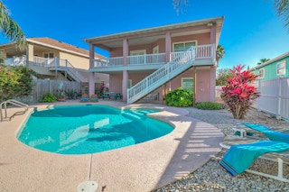 Large pink two story house with a pool in the backyard