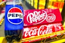 pepsi, dr peppers, and coca-cola products in a yellow shopping cart