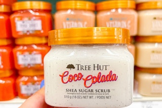 a hand holding a jar of body scrub