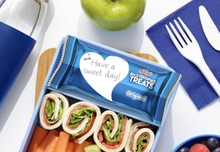 a Rice Krispies Treat in a lunch container at a table with food