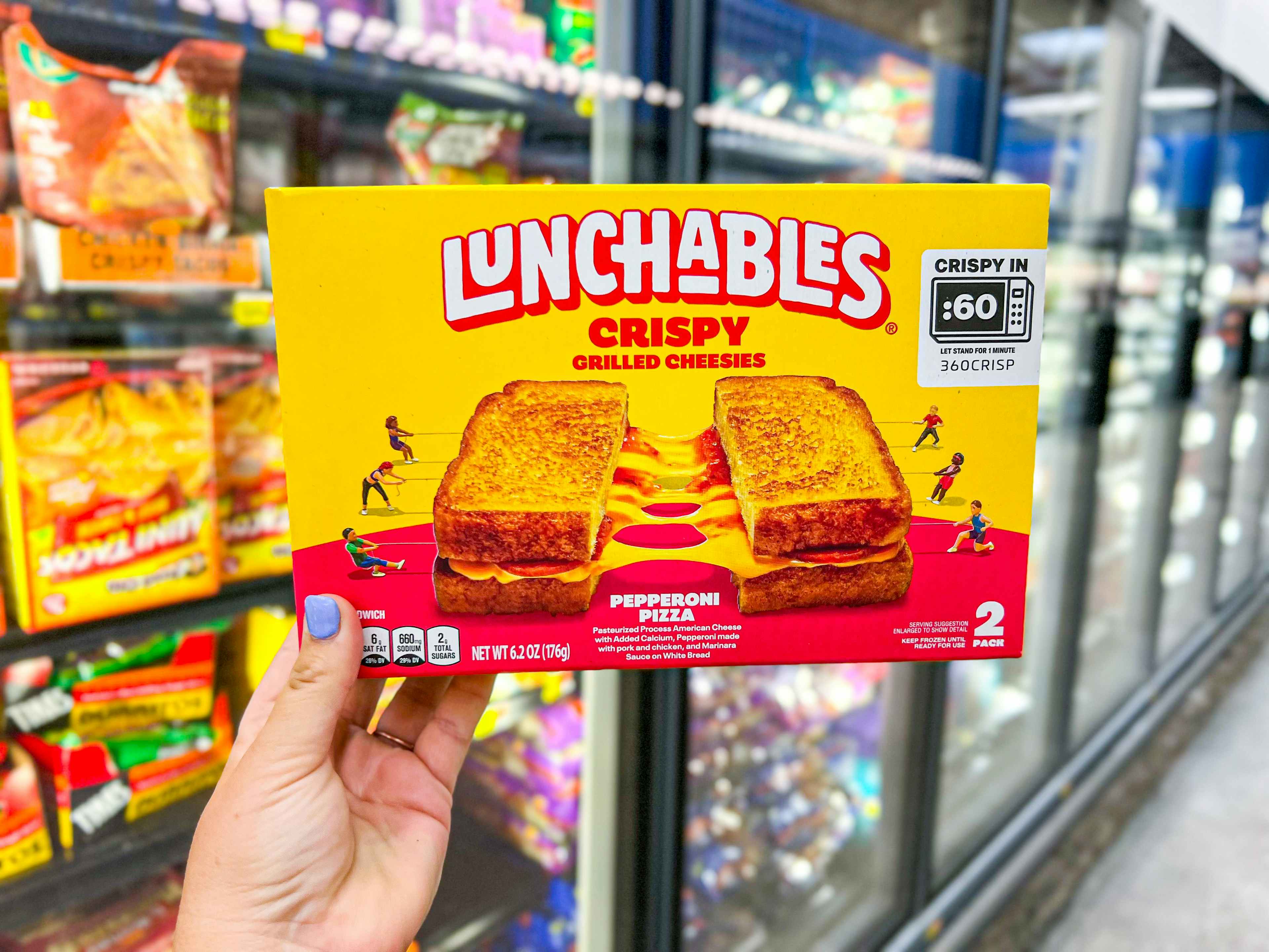 hand holding lunchables grilled cheesies box in walmart aisle