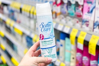 hand holding can of shaving cream in store aisle in front of product shelves with sales tags