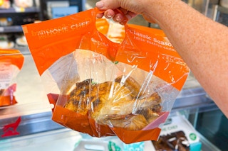 hand holding a whole roasted chicken