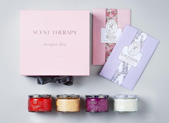 three colorful jars of candles next to a pink box