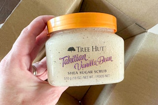 Hand holding Tree Hut Shea Sugar Scrub over Amazon box