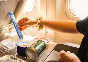 a person on a plane holding a tube of travel mouthwash