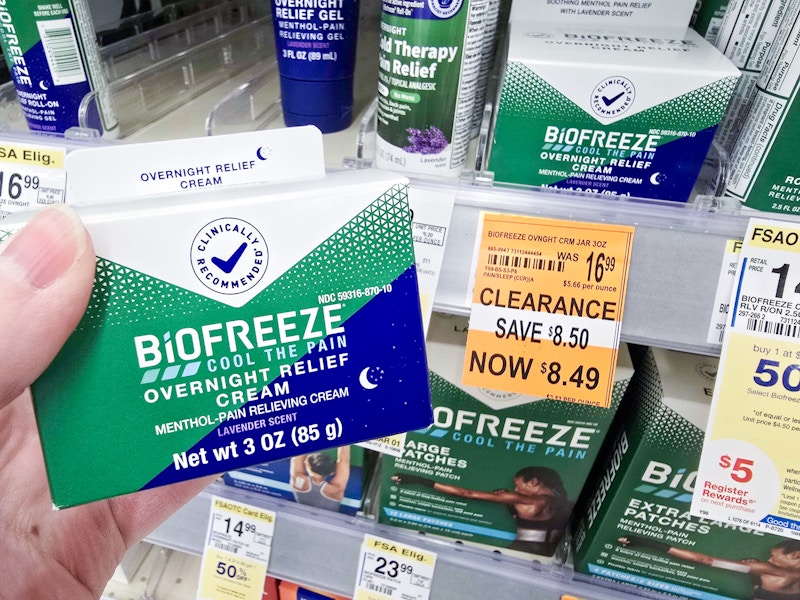 person holding biofreeze cream by a $8.49 clearance sign