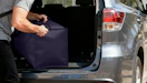 a person puling a moving bag out of a trunk